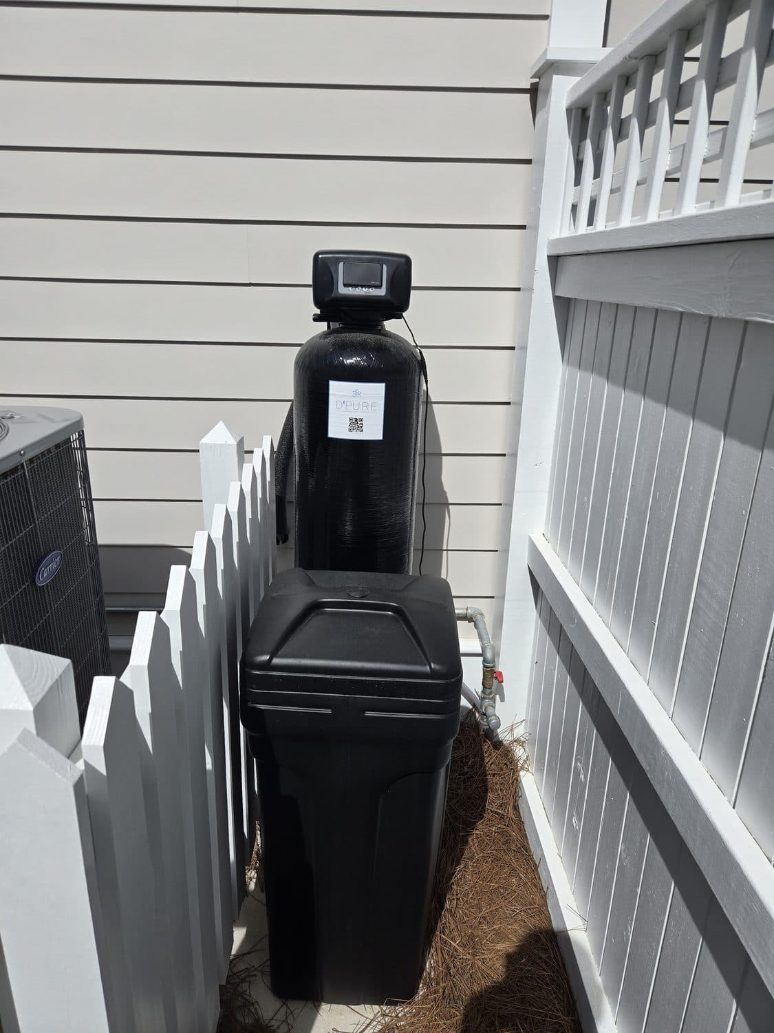 D'Pure water softener with a branded service tag installed at a home